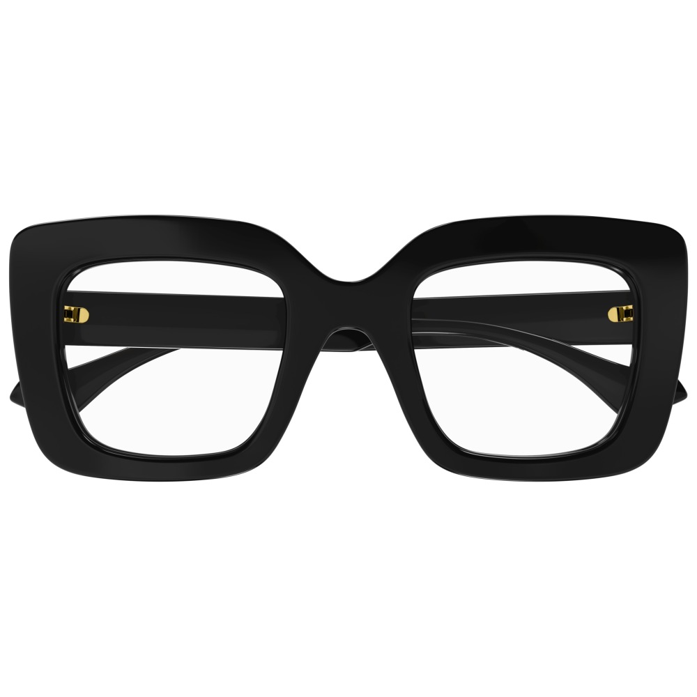 Occhiali neri oversize, montatura rettangolare spessa, dettagli dorati sulle aste. Eleganti e moderni.